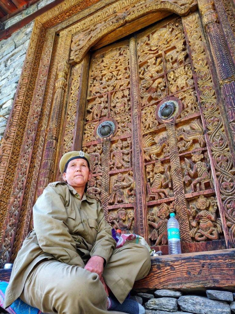A lady sitting at hand-carved wooden entrance door of Kamru Fort.