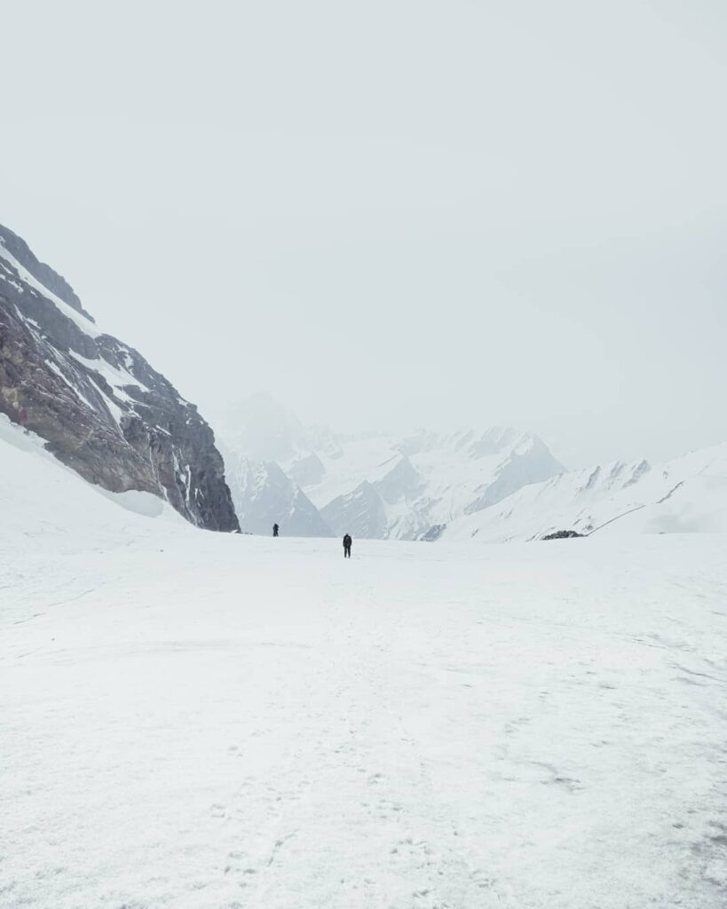 A hiker walking on Khatling Glacier snowfields